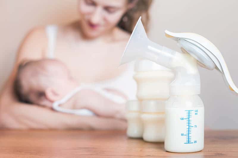 Mom pumping and breastfeeding her baby at home