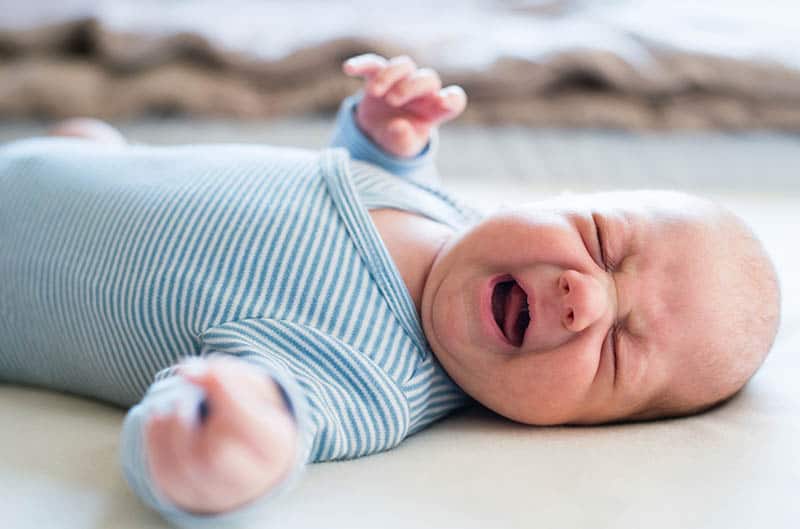 baby is crying while lying on bed