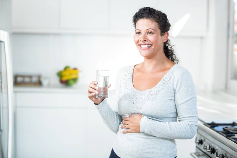 young pregnant woman holding a glass of water