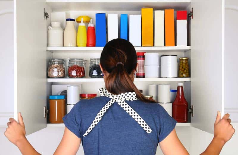 Woman opening the doors to a fully stocked pantry