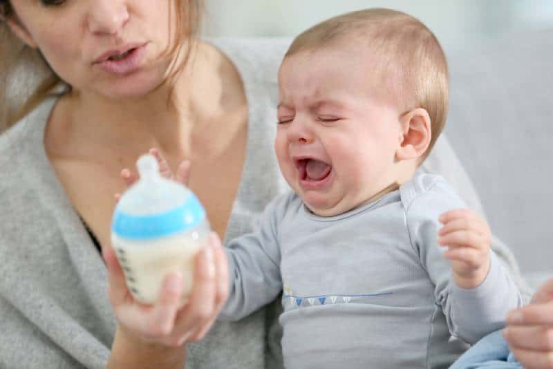 Baby boy crying while mom is holding him