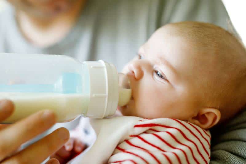 Father feeding newborn baby daughter with milk in nursing bottle