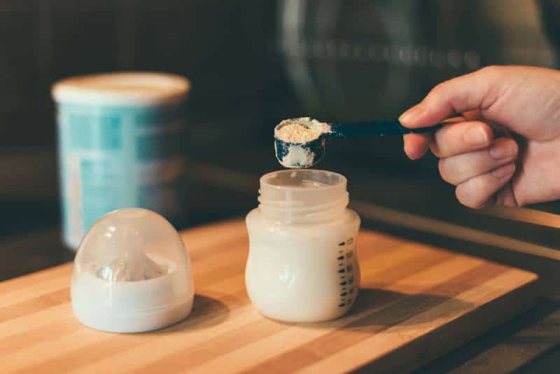 Mère préparant du lait maternisé dans un biberon de lait