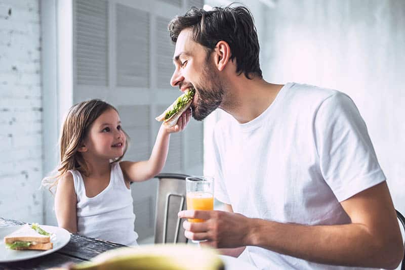 father and daughter eating a sandwich