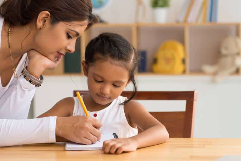 woman helping her daughter with homework 