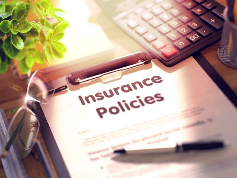 Insurance policies on clipboard with paper sheet on Table with office supplies around.