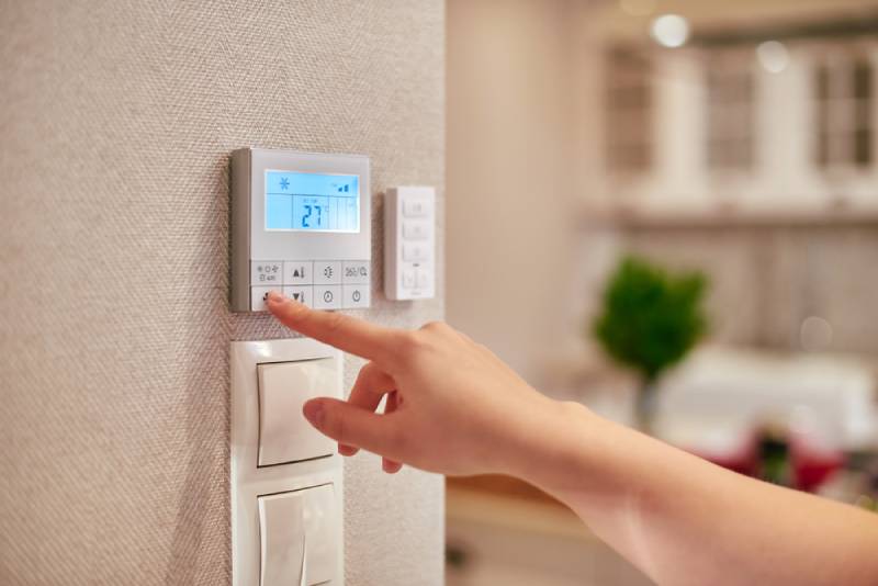 Woman hand adjusting temperature in her home