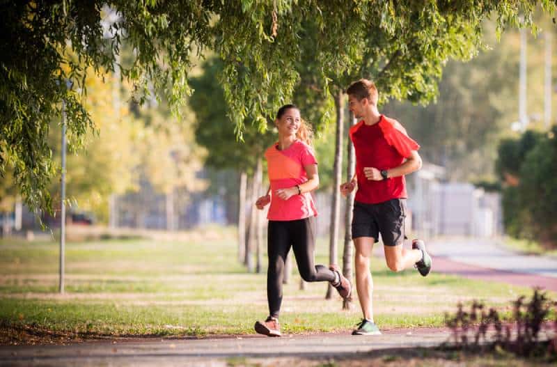 sportive couple running in park and watching at each other