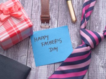 Happy Father's Day inscription with tie and watch on wooden background