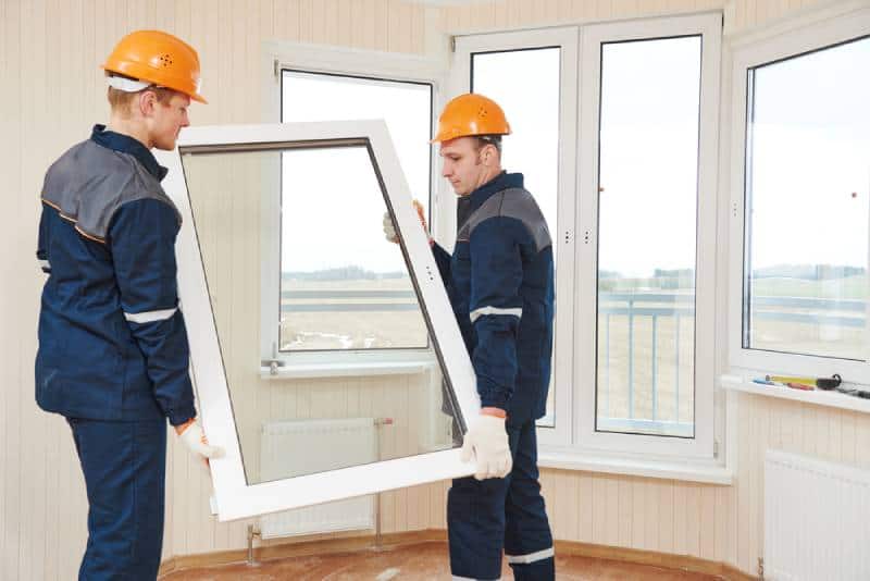 2 Workers are installing new windows in a house