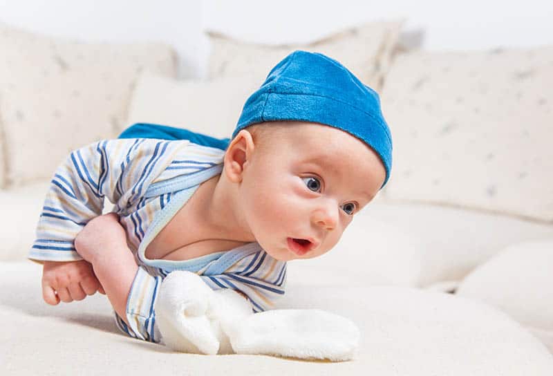 cute baby in blue hat rolling over