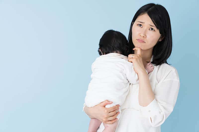 asian woman worried thinking about giving up breastfeeding 