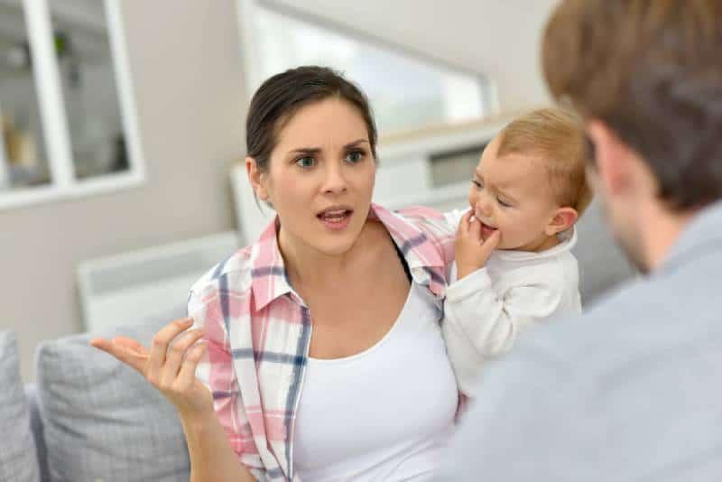 Man and woman arguing in front of baby at home