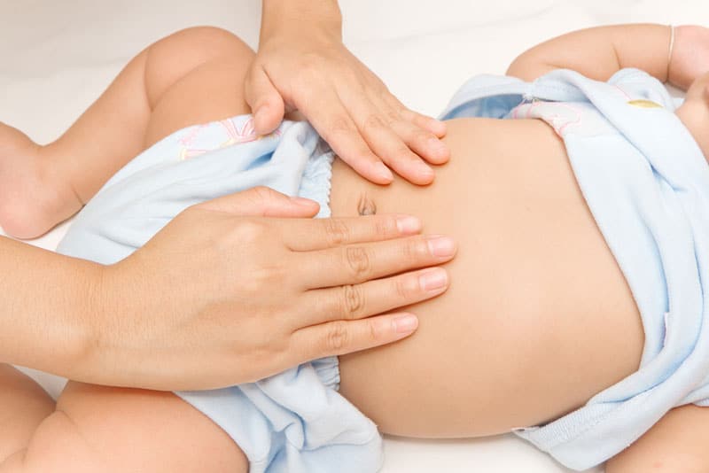 mother giving tummy massage to her baby