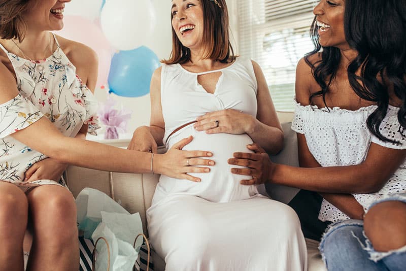 two friends cuddling pregnant woman