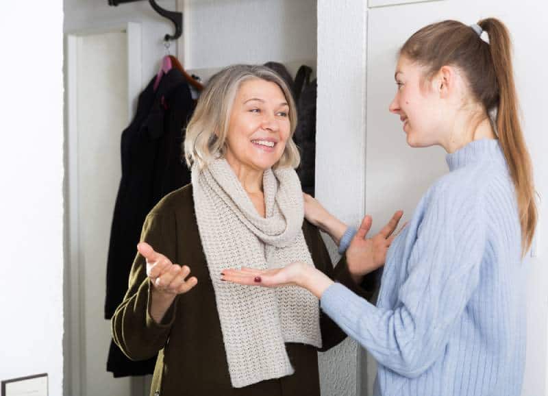 Junge und ältere Frauen führen emotionale Gespräche im Wohnungsflur