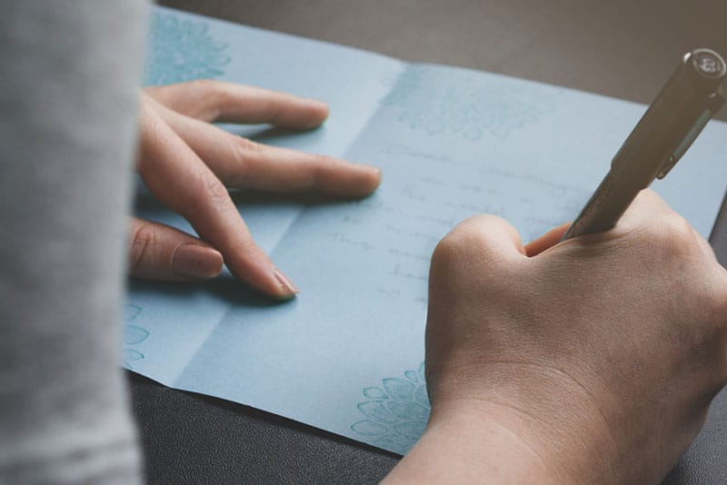 woman writing congratulation card