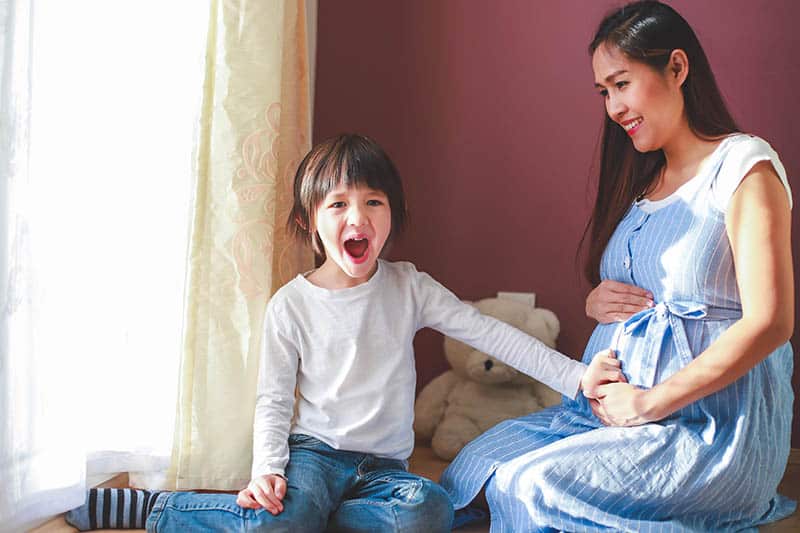 happy boy feeling baby moving in mothers belly