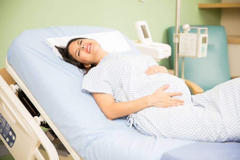pregnant woman getting labor contractions while lying on a hospital bed