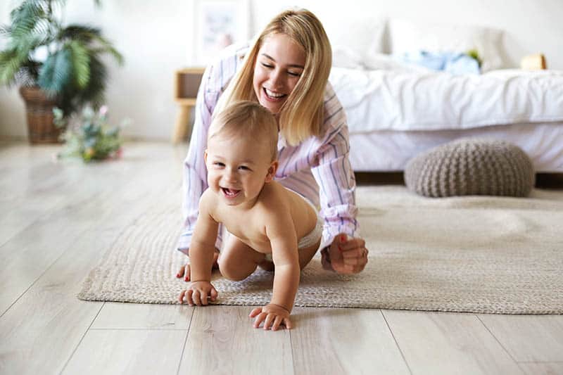 happy mother and baby while baby crawling