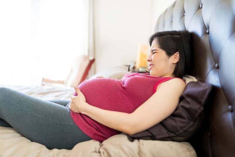 woman having contractions while lying on bed