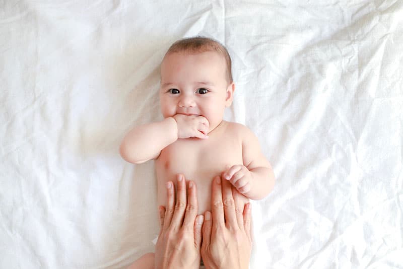 cute baby enjoying the belly massage by his mother