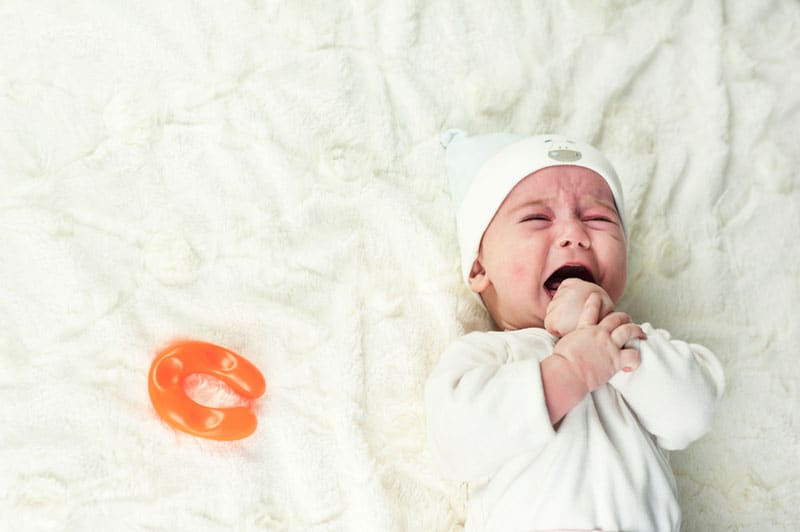 little baby lying on bed and crying