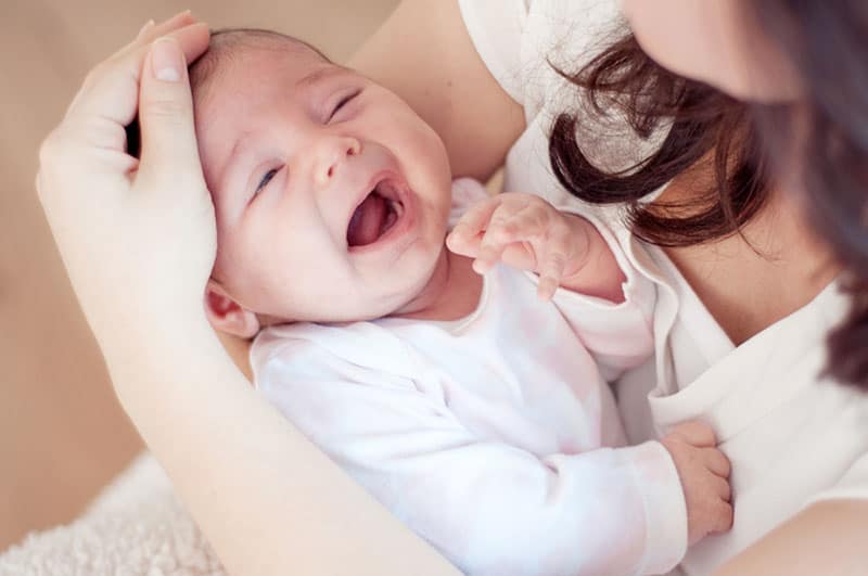 mother cuddling crying baby in arms