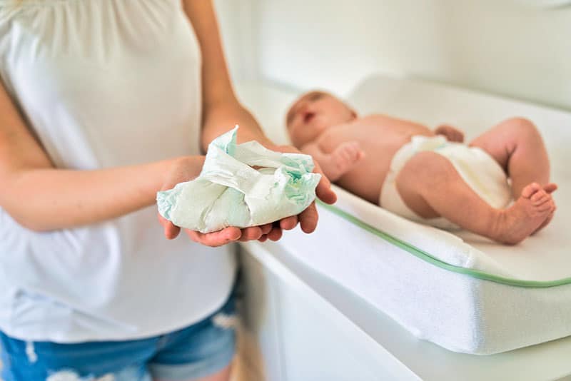 mother holding changed diaper of her baby in nursery