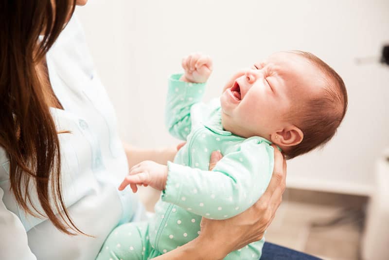 young mother holding crying baby in hands