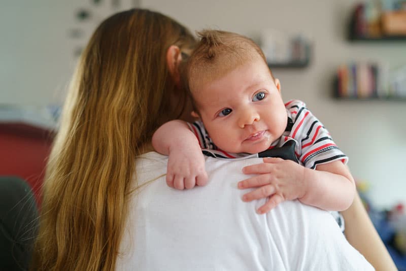 young mother trying burping the baby