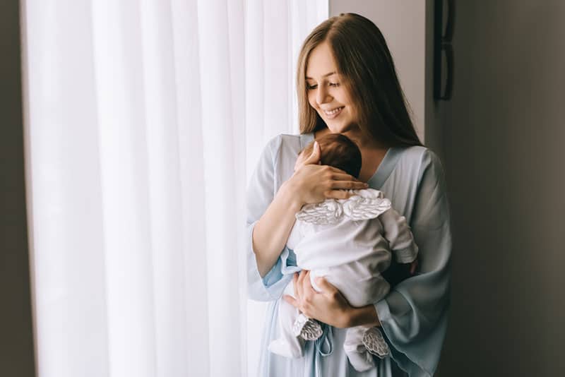 young smiling mother carrying her baby