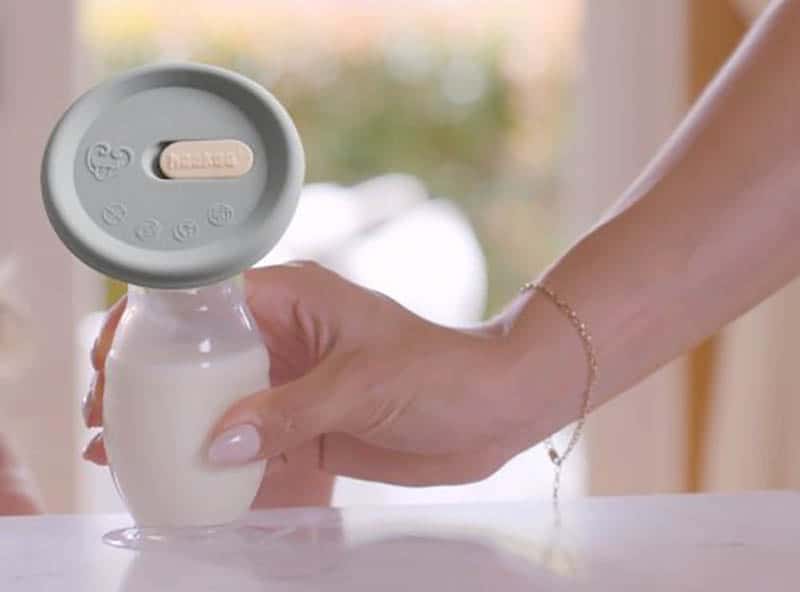 woman holding haakaa breast pump full of breast milk