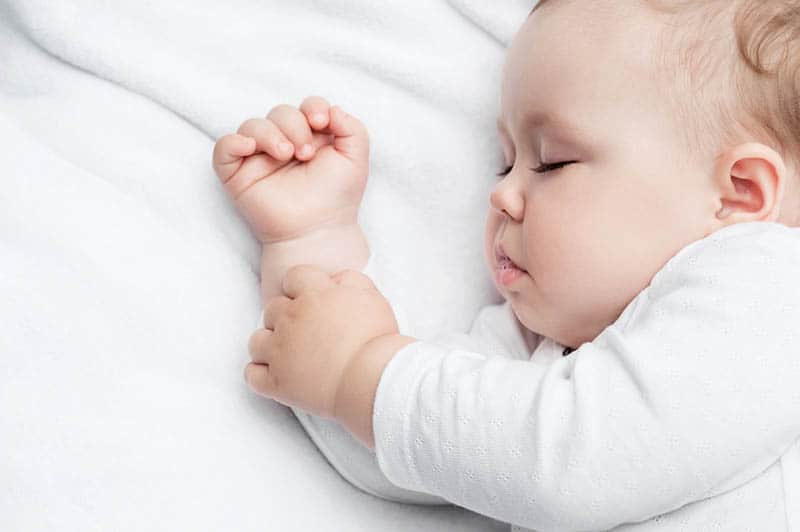 adorable baby with chunky cheeks sleeping in bed