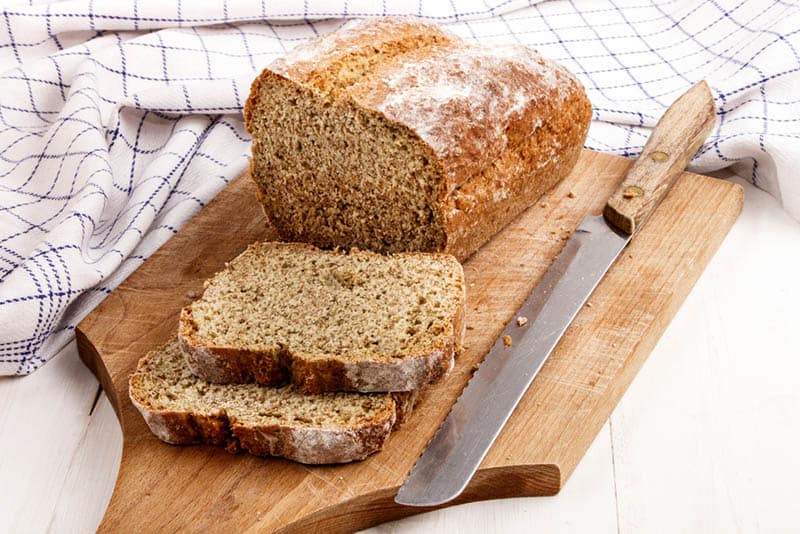 sliced wholemeal bread with knife on the wooden board with table cloth
