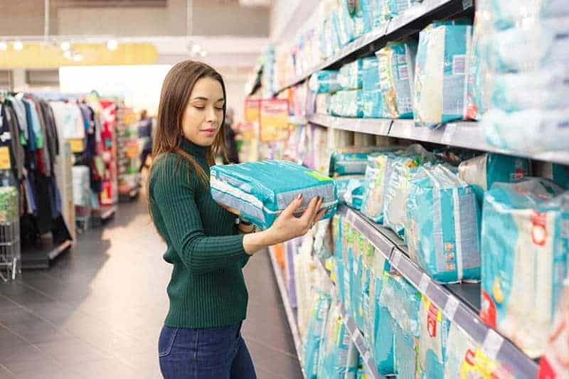 young woman checking baby diapers to buy in the store