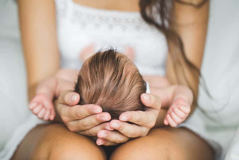 Loving mother hand holding sleeping newborn baby child