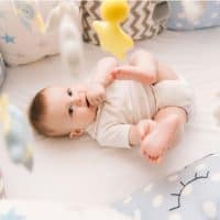 baby lying in the crib and looking up at a mobile