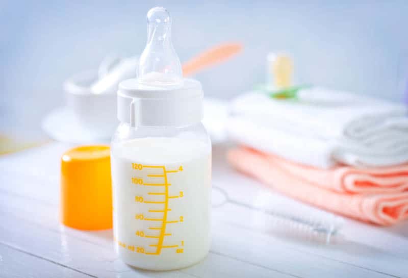 baby bottle with milk and baby items on the table
