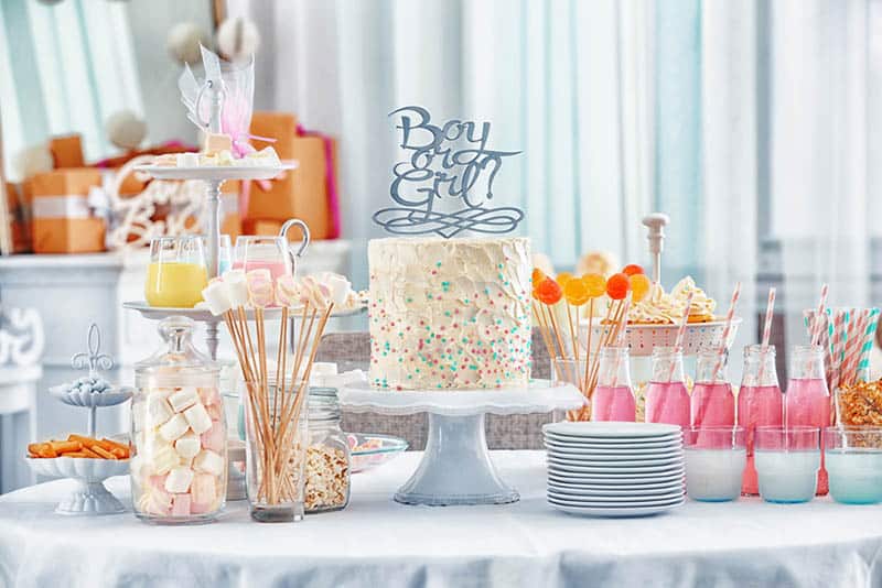 cake and different treats for baby shower party on table 