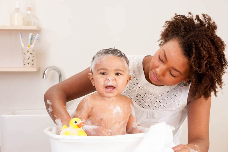  mère lavant un bébé mignon recouvert de shampooing 