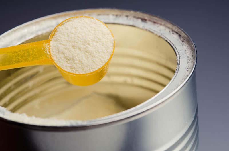 spoon with infant formula above the can on the table