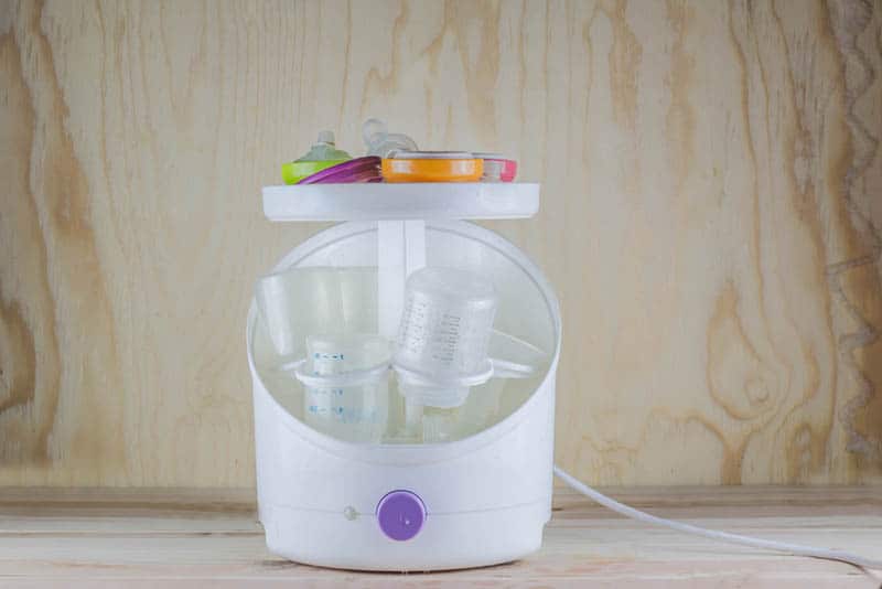 white sterilizer and dryer for baby milk bottles on the table