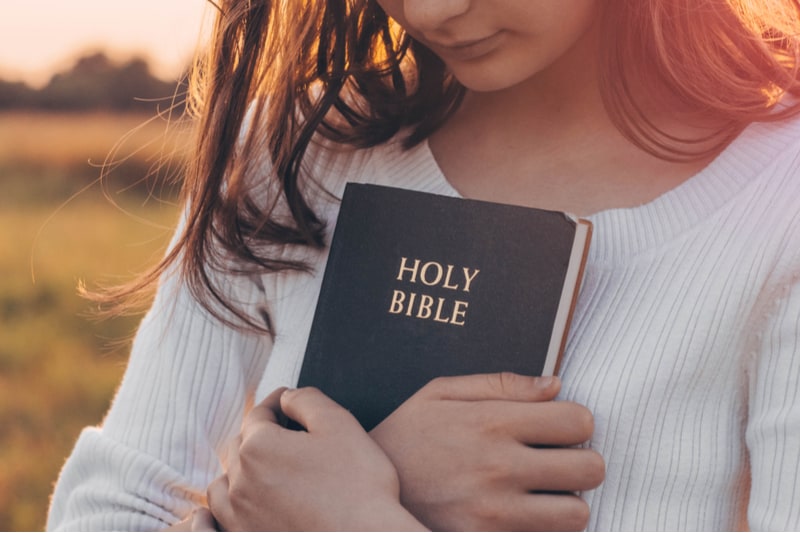 Christian teenage girl holds bible in her hands