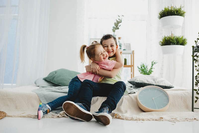 adorable little girl hugging with her brother on the couch