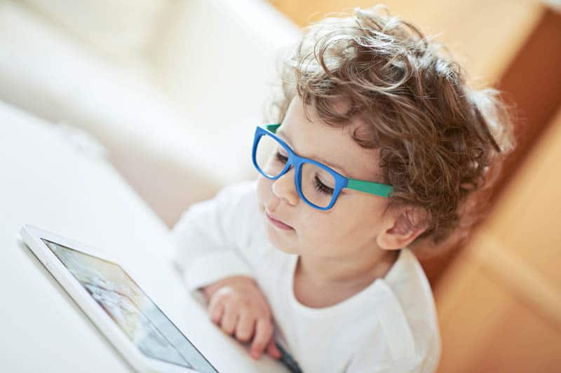 cute little boy with glasses watching tablet