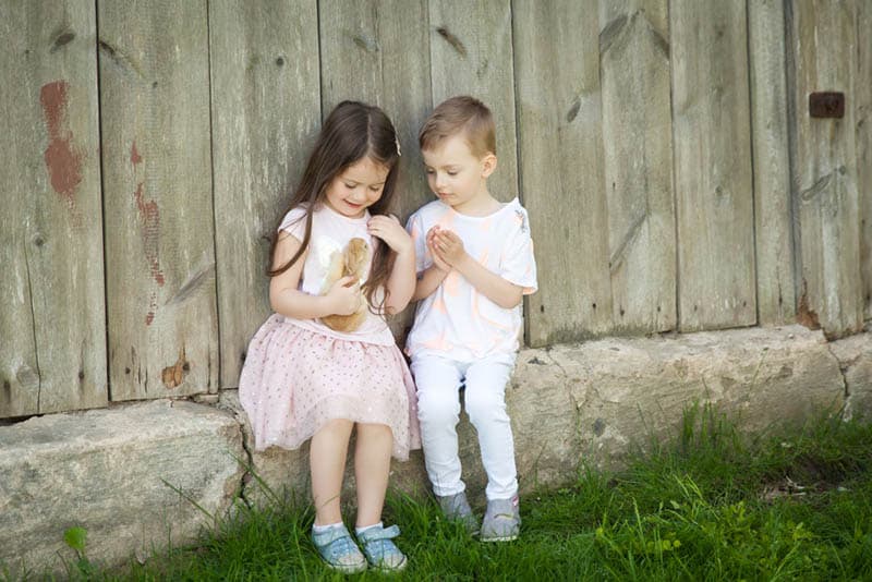 cute siblings playing with rabbit outdoor