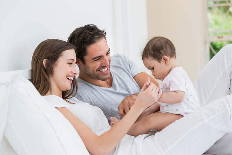 happy parents playing with their baby on the couch at home