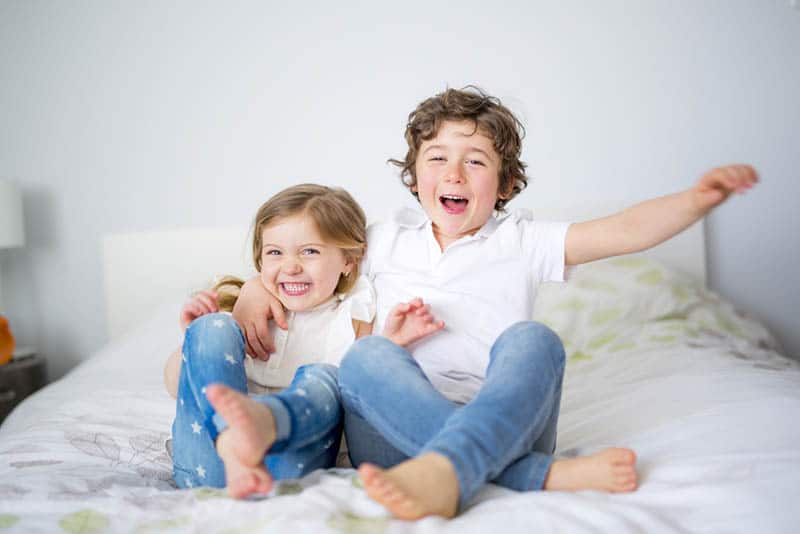 happy siblings hugging on the bed in bedroom