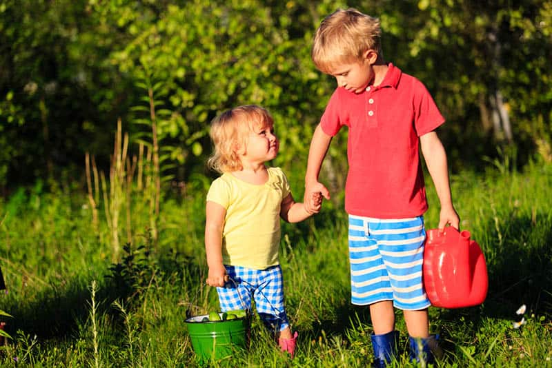 older brother holding for hand his little brother in the garden